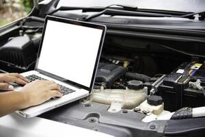 Professional mechanic checking car engine search for data with laptop and connect data system on car photo