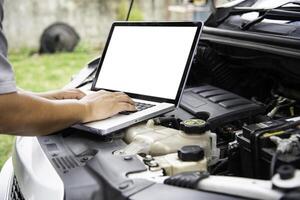 Professional mechanic checking car engine search for data with laptop and connect data system on car photo