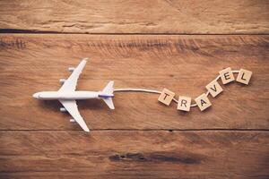 Airplane with the text  Travel  placed on a wooden floor. Travel ideas photo