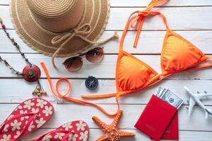 Beauty orange bikini and accessories on wooden floor for trip on summer photo