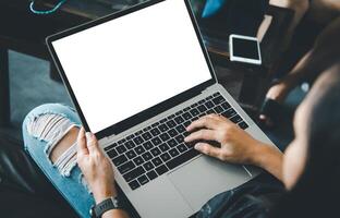 Mockup image of a woman's hand working on a laptop with blank white desktop copy space screen on a desk photo