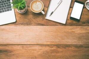 top view Office equipment including Laptop, mobile phone, mouse, notebook, coffee cup on the wood floor photo