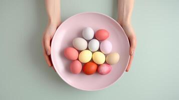 AI generated Two hands holding a pink plate filled with colored Easter eggs on a soft green background. Top view. Suitable for Easter event promotions and seasonal decor themes photo