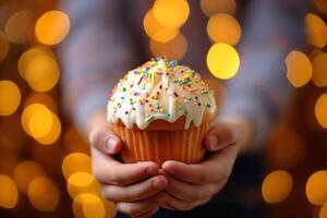 AI generated Child holding in his hands Easter cupcake Kulich decorated with white dripping icing and colored sprinkles. Blurred background. Ideal for bakery ads, holiday Easter content photo