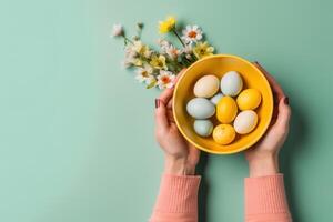 AI generated Hands holding bowl with colorful painted Easter eggs, against a light green blue background with flowers. Top view. Banner with copy space. For Easter promotions photo