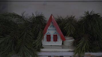 a toy house in Christmas tree branches. Decoration for Christmas video