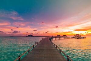 Amazing sunset panorama Maldives. Luxury resort villas pier path seascape soft led lights under colorful sky. Beautiful twilight sky fantastic clouds. Majestic beach background best vacation holiday photo