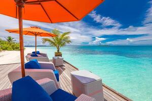 de madera cubierta embarcadero sillas debajo paraguas con Oceano ver en tropical isla. lujo recurso verano, frío relajarse vibras, vacaciones viaje paisaje foto