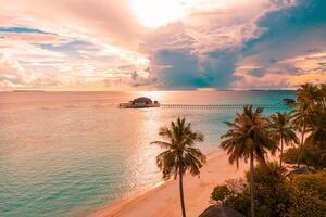 Aerial sunrise sunset beach bay view, colorful sky and clouds, wooden jetty over water bungalow. Meditation relaxation tropical drone view, sea ocean water. Aerial nature skyscape seascape background photo