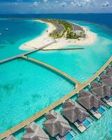 Aerial view of Maldives island, luxury water villas resort and wooden pier. Beautiful sky and ocean lagoon beach background. Summer vacation holiday and travel concept. Paradise aerial landscape pano photo