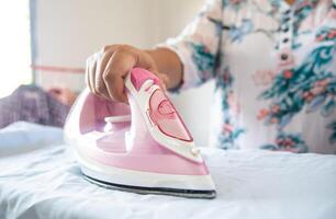 Close up of woman ironing clothes on ironing board photo