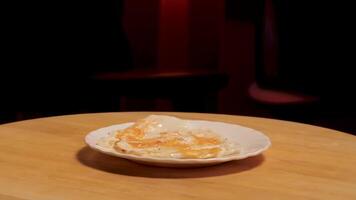 Fried egg on a plate rotating on a wooden board on dark room background. Stock footage. Close up of white glass plate with fried egg on it. video