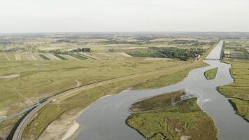 aérien vue de grand rivière entouré par agriculture des champs contre gris nuageux ciel. action. aérien vue de rural paysage. video