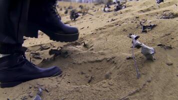 schließen oben von Frau Füße im schwarz Stiefel Gehen auf Sand mit trocken Blätter. Lager Filmaufnahme. weiblich tragen Leder schwarz Stiefel Gehen auf sandig Küste. video