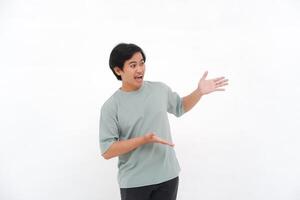 Excited Asian male employee wearing a T-shirt pointing at the copy space beside him, isolated by a white background photo