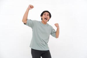 Young Asian man with an enthusiastic expression as if feeling victorious, depicting a sense of great satisfaction. photo