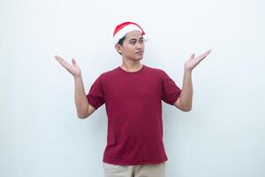 Young Asian man wearing a Santa Claus hat smiling, shock and pointing to her side isolated by white background for visual communication photo