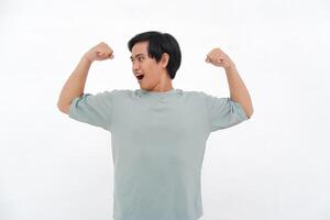 joven asiático hombre levanta mano, expresando fuerza con variado emociones desde sonrisas a ira foto