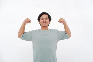 joven asiático hombre levanta mano, expresando fuerza con variado emociones desde sonrisas a ira foto