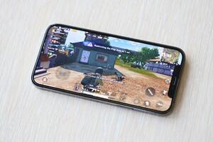 PUBG PlayerUnknowns Battlegrounds mobile iOS game on iPhone 15 smartphone screen on wooden table during mobile gameplay photo