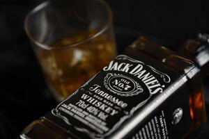 KYIV, UKRAINE - MAY 4, 2022 Jack Daniels original alcohol bottle on wooden table with black fabric photo