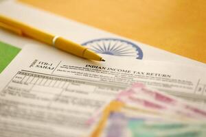 KYIV, UKRAINE - MAY 4, 2022 Indian income tax return blank form with pen and indian rupees bills photo