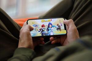 Fantasy Westward Journey mobile iOS game on iPhone 15 smartphone screen in male hands during mobile gameplay photo