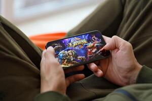 Honor of Kings mobile iOS game on iPhone 15 smartphone screen in male hands during mobile gameplay photo