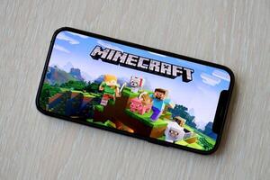 Minecraft mobile iOS game on iPhone 15 smartphone screen on wooden table during mobile gameplay photo