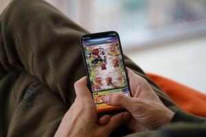 Monster Strike mobile iOS game on iPhone 15 smartphone screen in male hands during mobile gameplay photo