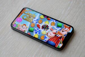 Candy Crush Saga mobile iOS game on iPhone 15 smartphone screen on wooden table during mobile gameplay photo