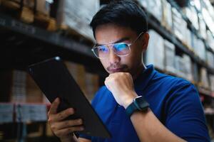 Warehouse workers in blue uniforms use digital tablets to check inventory in a large warehouse. Distribution center. Logistics and export business. photo