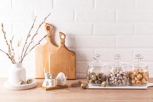 Stylish kitchen background for the Easter holiday. jars for bulk products, cutting boards, a vase with willow sprigs, Easter eggs and bunnies. photo