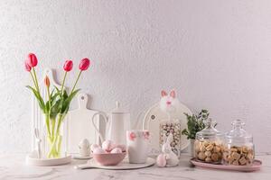 Chic kitchen background in delicate pastel colors, decorated for the Easter holiday with rabbits, flowers, eggs. White cookware. photo