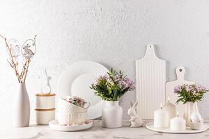 Chic kitchen background in delicate pastel colors, decorated for the Easter holiday with rabbits, candles, flowers, eggs. White cookware. photo