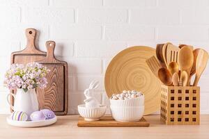 cocina de madera encimera con cocina utensilios y festivo decoraciones para el primavera Pascua de Resurrección día festivo. frente vista. blanco ladrillo pared. foto