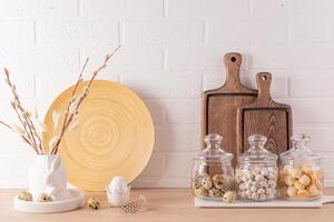 Kitchen wooden countertop with kitchen utensils and festive decorations for the spring Easter holiday. Front view. White brick wall. photo