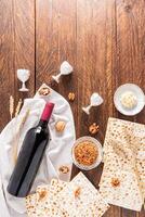 Traditional treats for the Jewish Passover holiday. matzoth , walnuts, a bottle of wine, parsley root. Top vertical view. Wooden background. photo