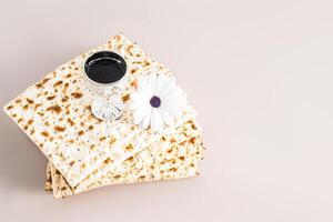 A stack of freshly baked matza and a silver shot glass with red wine and a spring flower. The holiday of the Jewish Passover. minimalism. pastel photo