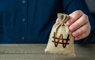 A man holds out a south korean won money bag. Economics and currency exchange, stock market. Deposits and savings. Banks and finance. Investments, fundraising. Funding and grants. Loans, mortgage. photo