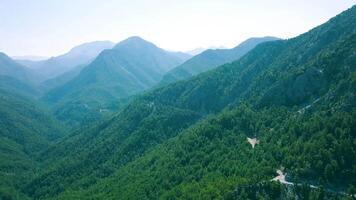 Top view of beautiful green mountain scenery. Clip. Beautiful mountain valleys with green cover on sky background. Roads passing through mountain valleys are perfect for summer travel video