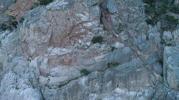 Steep cliff with ledges. Shot. Top view of rocky steep wall with sparse vegetation on ledges. Erosion creates loose unstable surface of rocky massif video