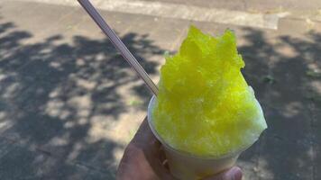 A shaved ice of lemon syrup with left hand sunny day close up video