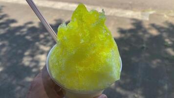 A shaved ice of lemon syrup with left hand sunny day close up video