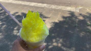 A shaved ice of lemon syrup with left hand sunny day close up video