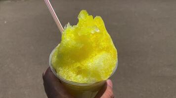 A shaved ice of lemon syrup with left hand sunny day close up video