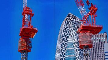 een timelapse van kraan Bij de top van de gebouw in tokyo telefoto schot kantelen video