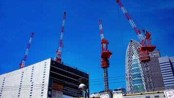 een timelapse van kraan Bij de top van de gebouw Bij de bedrijf stad- in tokyo breed schot kantelen video