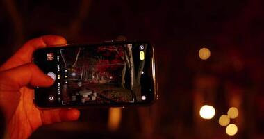 un' smartphone tiro illuminato rosso le foglie a il parco nel kyoto nel autunno a notte video