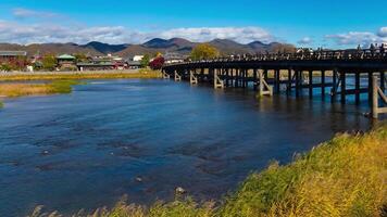 un' lasso di tempo di nube e turisti vicino togetsukyo ponte nel kyoto largo tiro panning video